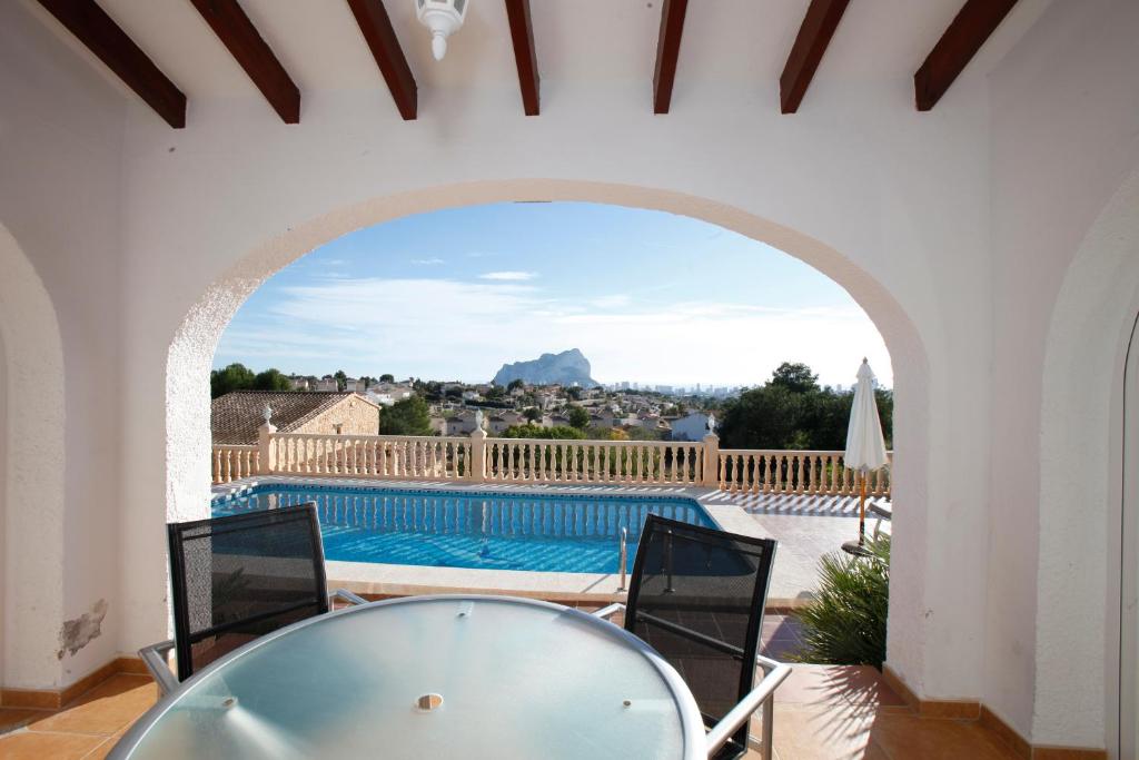 uma vista para uma piscina a partir de uma casa com um arco em Villa Robin - Costa CarpeDiem em Calpe