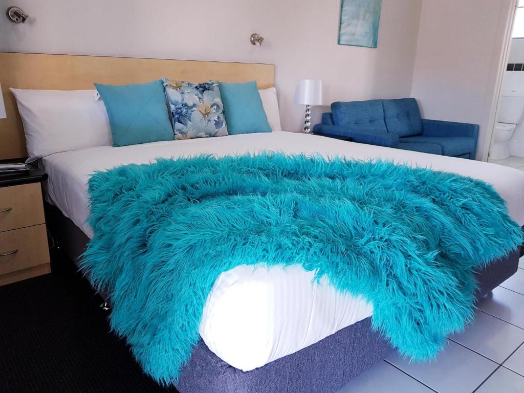 a blue faux fur blanket on a bed at Alara Motor Inn in Mackay