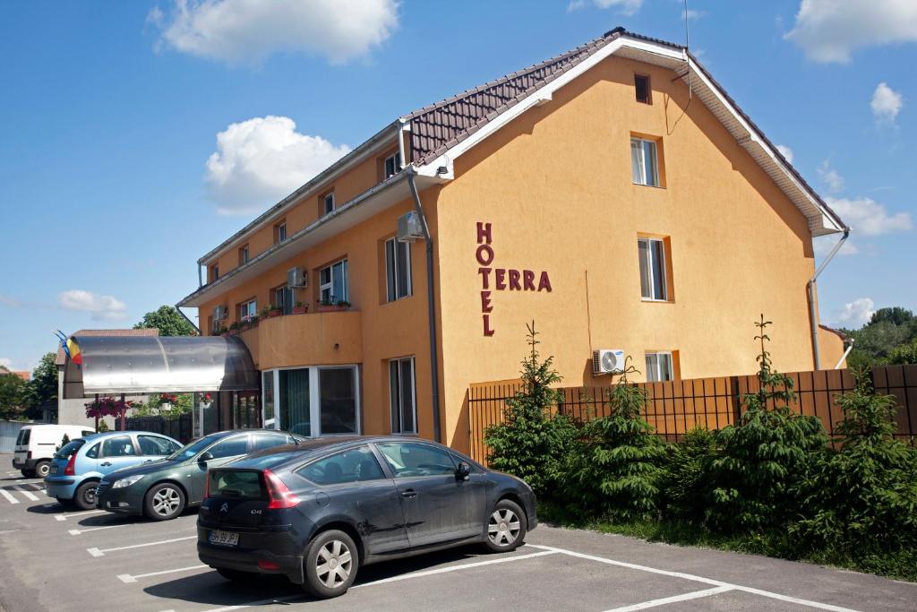 a building with cars parked in a parking lot at Hotel Terra in Oradea