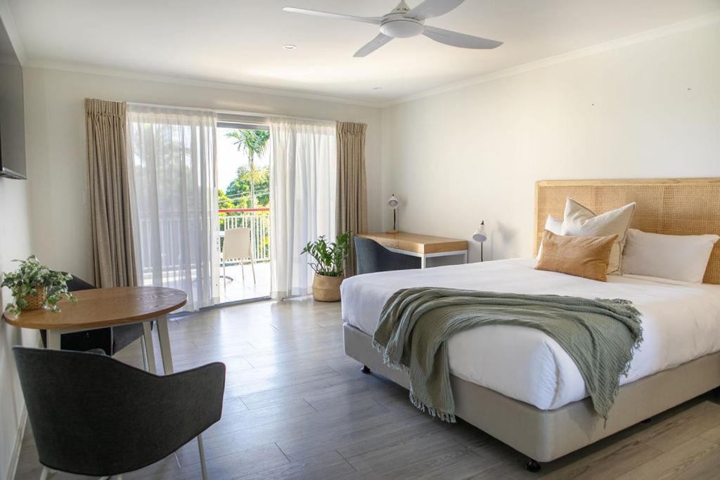 1 dormitorio con cama, mesa y ventana en Noosa Heads Motel, en Noosa Heads