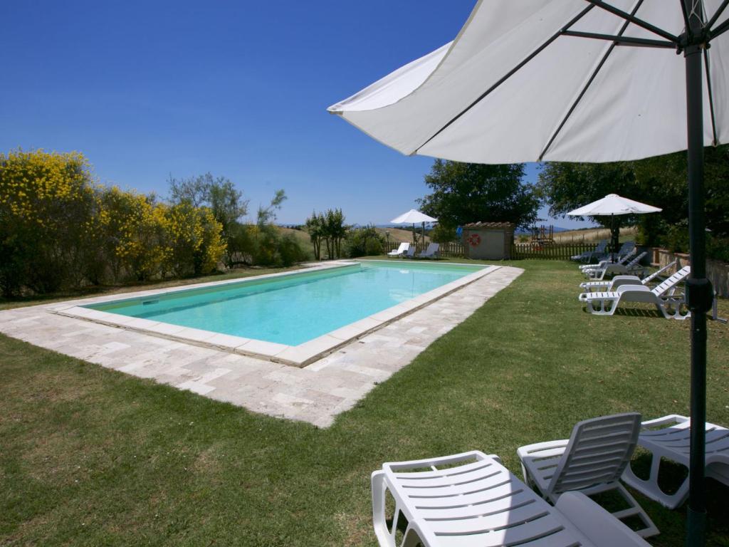 een zwembad met ligstoelen en een parasol bij Belvilla by OYO Farmhouse in Tuscany with Garden in Castelnuovo Berardenga