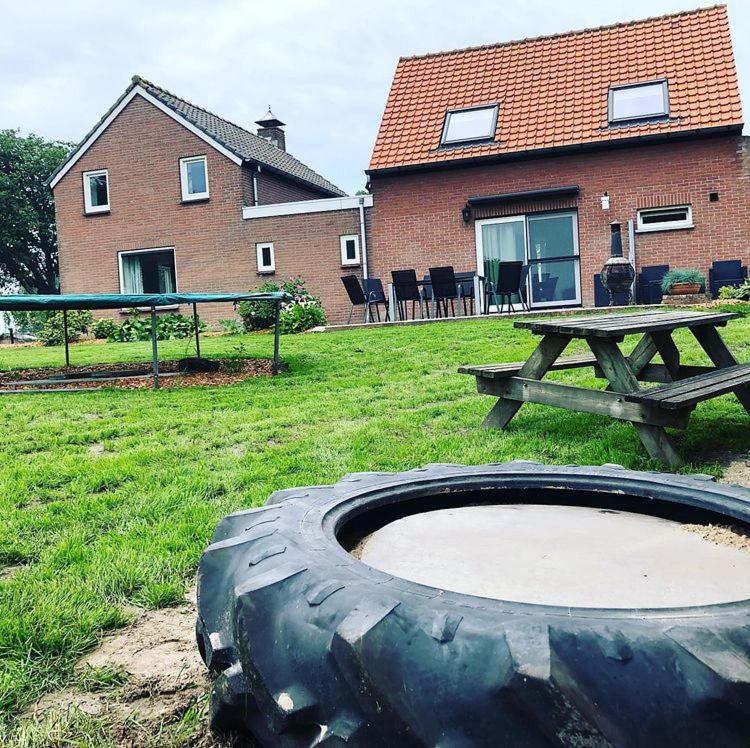 a large tire sitting in the grass next to a picnic table at Huisje op den Diek in Sint Kruis
