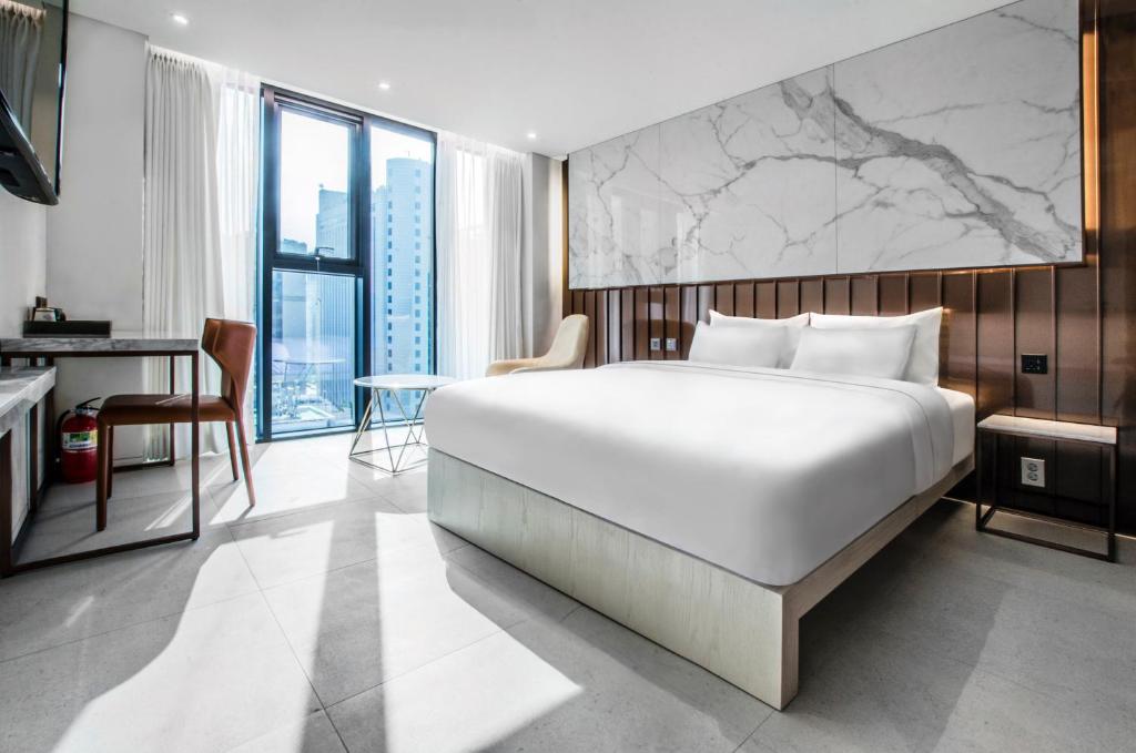 a bedroom with a large white bed and a desk at Hotel the Castle bangi 2nd in Seoul