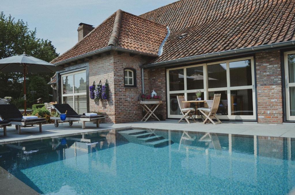 a house with a swimming pool with chairs and a table at La Maison Des Papillons in Deerlijk