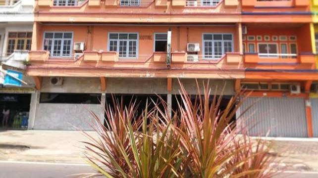 ein orangefarbenes Gebäude mit Fenstern und Pflanzen davor in der Unterkunft Hotel Mayang Sari 2 in Jambi