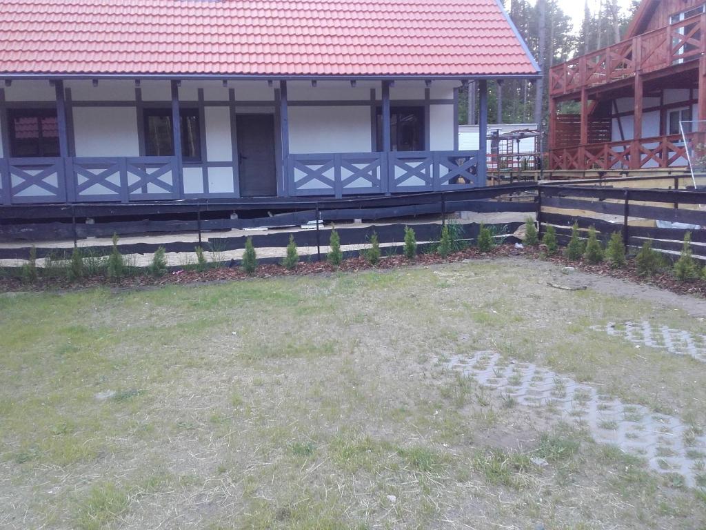 un cortile di fronte a una casa con tetto rosso di DOMEK U FLORIANA I KONRADA a Załakowo
