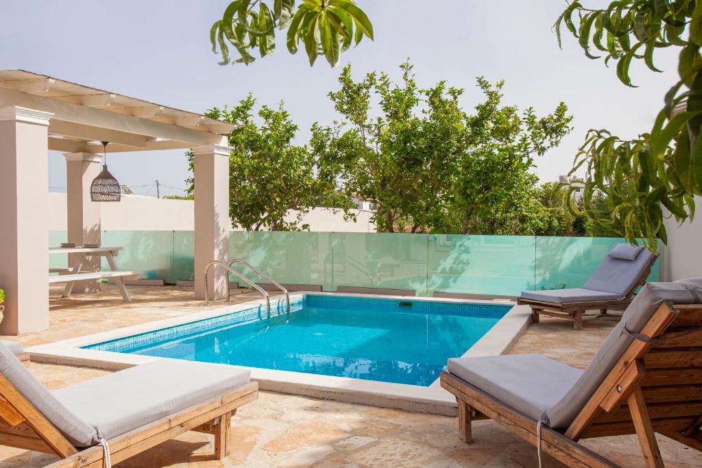 a swimming pool with two lounge chairs next to a house at Ninos Corfu Villas in Agios Georgios