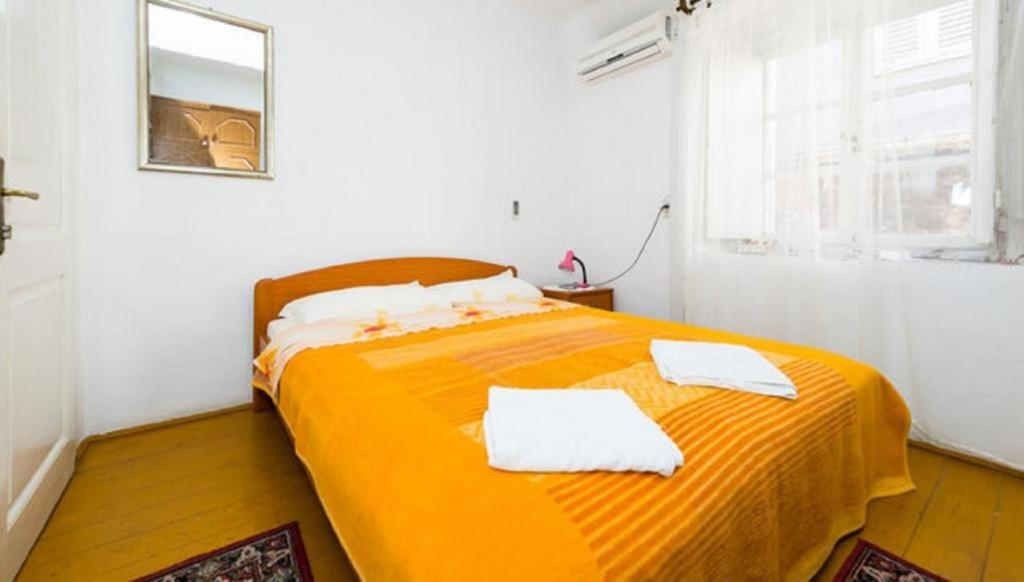 1 dormitorio con 1 cama naranja y 2 toallas en Rooms Kisic, en Dubrovnik