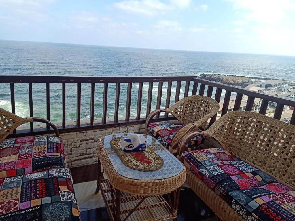 sporting sea view two bedroom appartement في الإسكندرية: بلكونة عليها كراسي وطاولة عليها قبعة