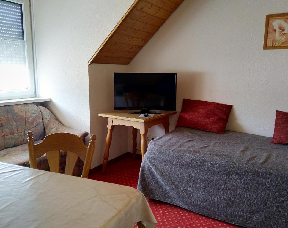 a bedroom with a bed and a desk with a tv at Pension Schneider, Ferienwohnung in Bad Gögging