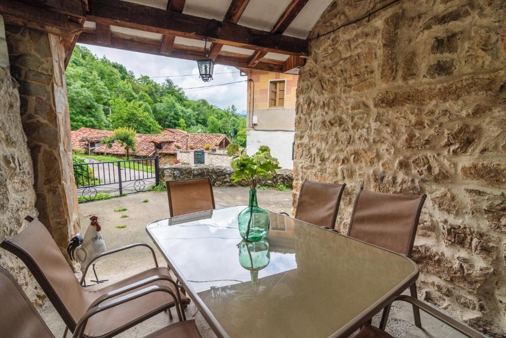 una mesa y sillas en una habitación de piedra con ventana en Casa Rural La Carrozal Senda del Oso, en Orelleiru