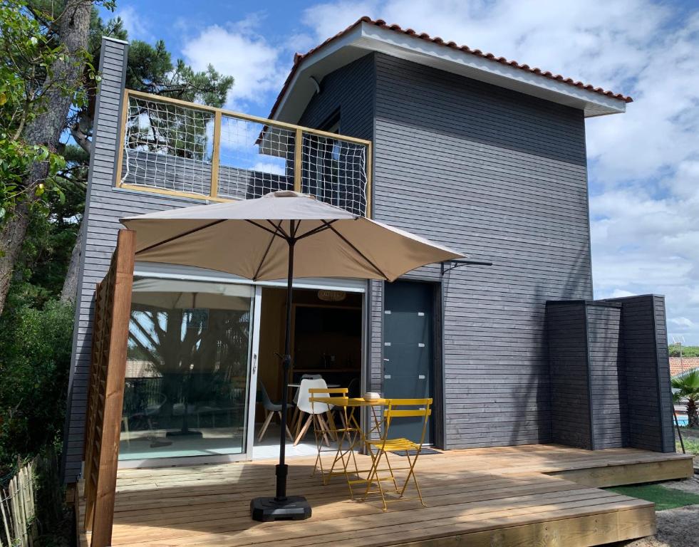 une maison avec une terrasse et un parasol dans l'établissement LE CHALET DE L'OCÉAN, à Lacanau-Océan