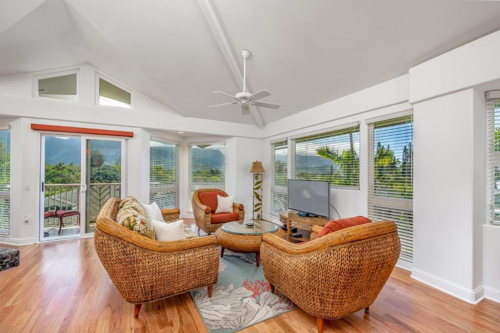 a living room with chairs and a tv and windows at Villas of Kamalii 17 condo in Princeville