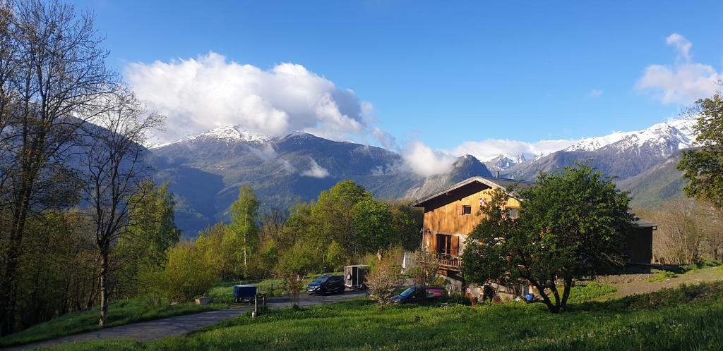 uma casa numa colina com montanhas ao fundo em Chambre d'hôtes à la ferme em Beaune