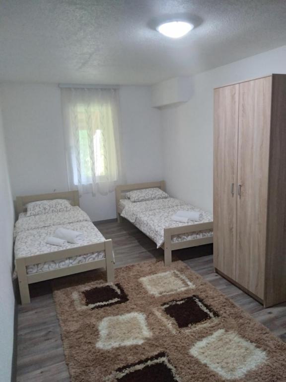a room with two beds and a cabinet and a rug at Guest house Erdan in Plav