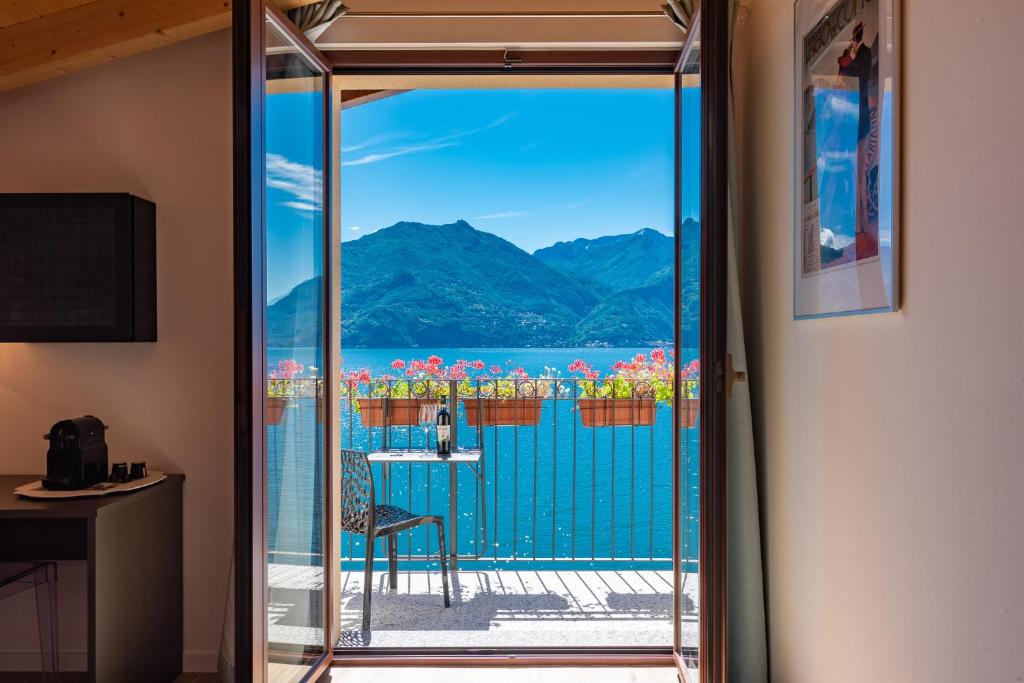 een kamer met een balkon met uitzicht op het water bij Foresteria Lago di Como in Menaggio