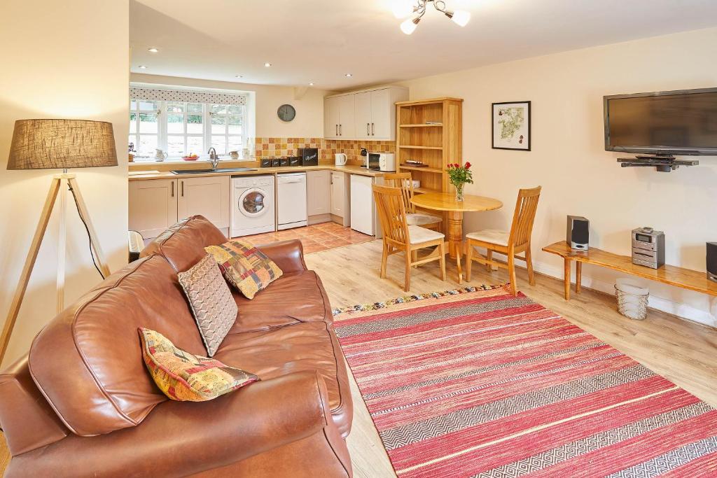 a living room with a leather couch and a kitchen at Host & Stay - Heron Cottage in Levisham