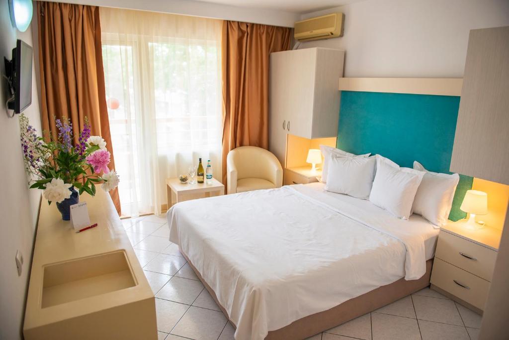 a hotel room with a bed and a vase of flowers at Hotel Majestic Mamaia Half Board & All Inclusive in Mamaia