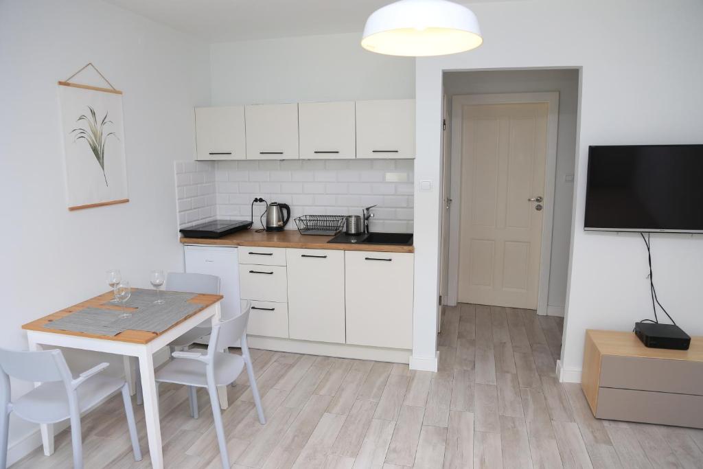 a kitchen with white cabinets and a table with chairs at Apartament Sopot in Sopot