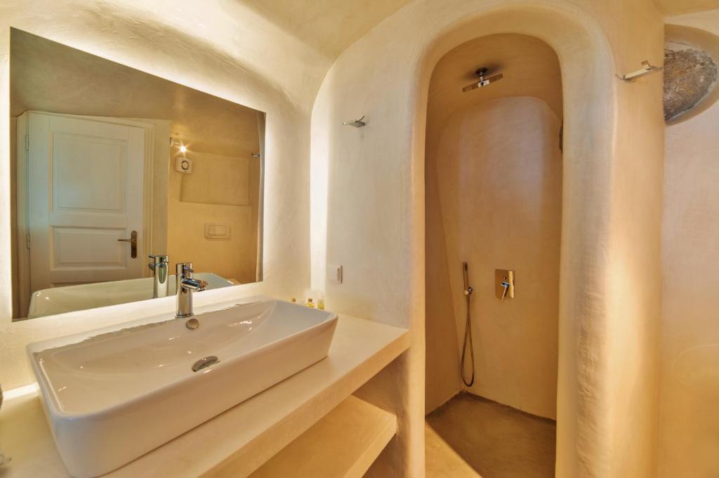 a bathroom with a tub, sink and mirror at Armeni Village in Oia