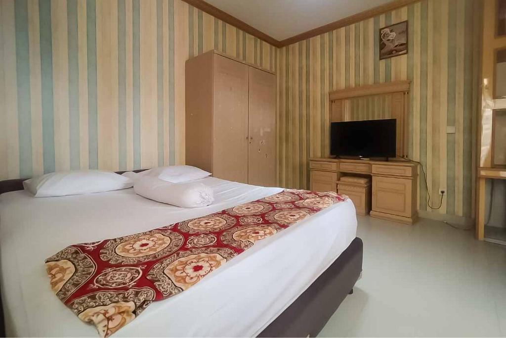 1 dormitorio con 1 cama y TV en d'H Mansion La Rosa Syariah Sentul Mitra RedDoorz, en Bogor