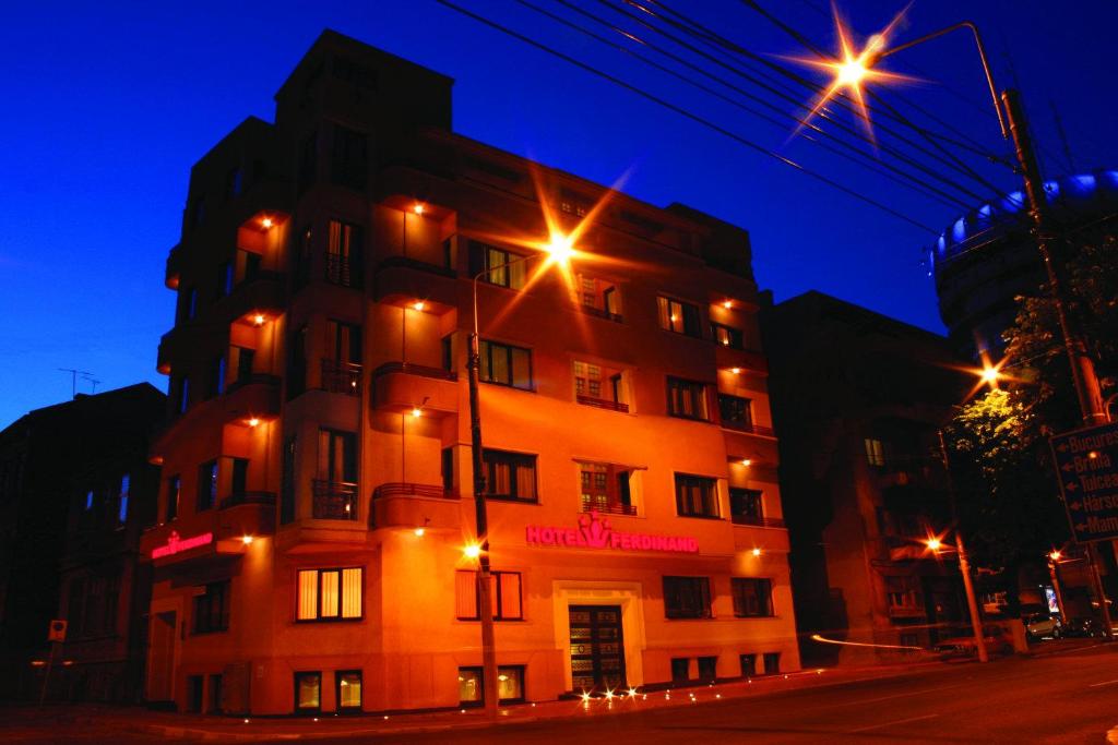un edificio se ilumina por la noche con luces de la calle en Hotel Ferdinand, en Constanţa