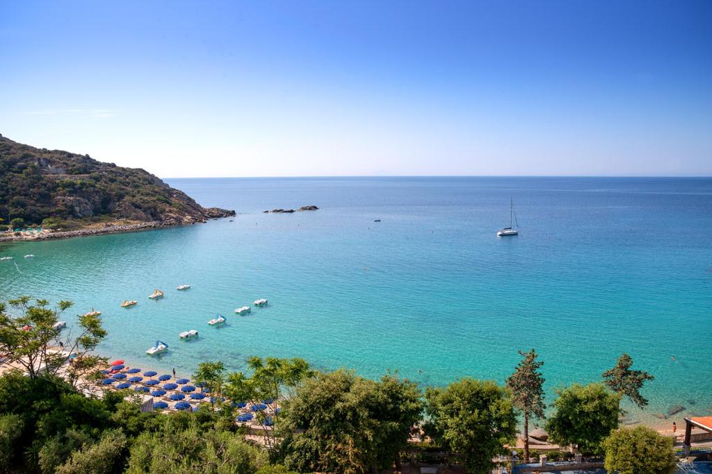 a beach with umbrellas and boats in the water at Hotel Baia Imperiale in Campo nell'Elba
