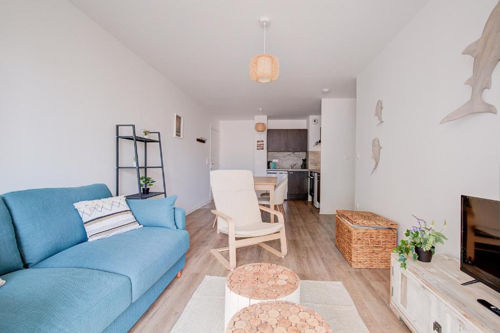 un salon avec un canapé bleu et une table dans l'établissement Ressourcez-vous dans ce bel appartement à Lacanau, à Lacanau