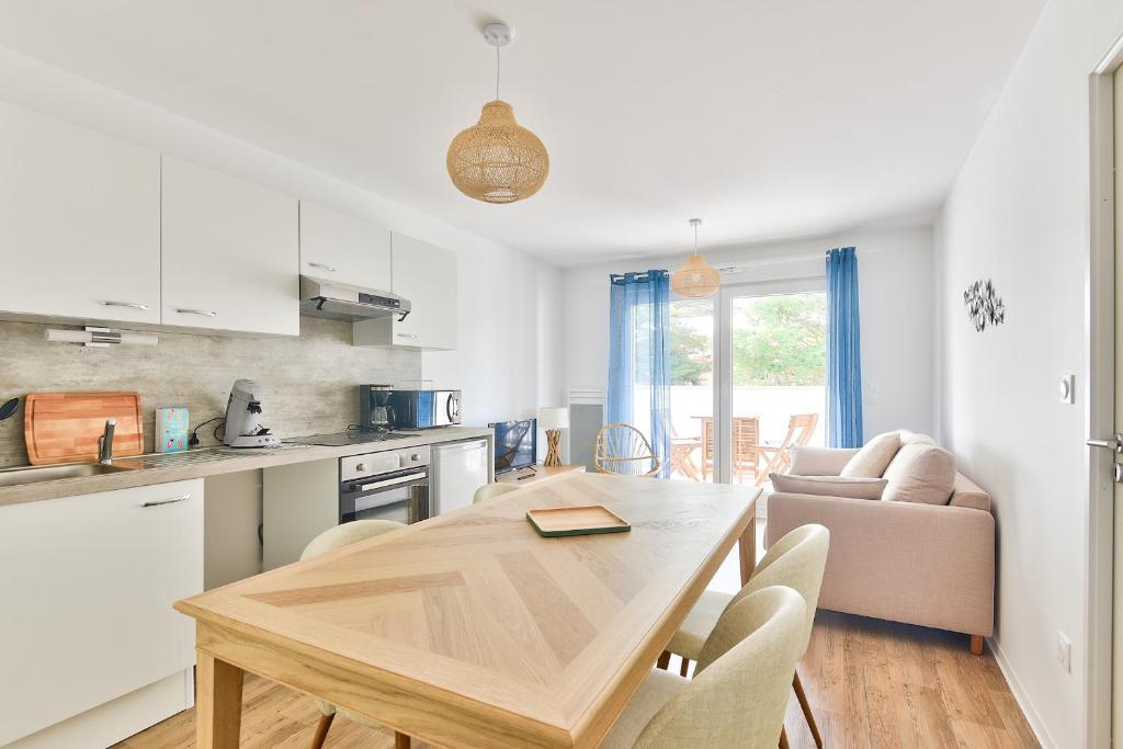 une cuisine et une salle à manger avec une table et des chaises dans l'établissement Confort et bel appartement au coeur de Lacanau, à Lacanau