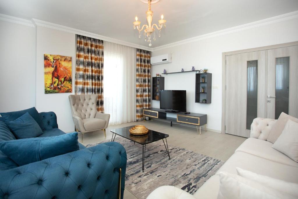 un salon avec un canapé bleu et une télévision dans l'établissement Leena suites, à Trabzon
