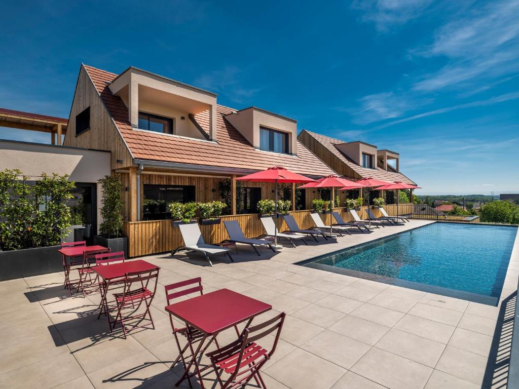 eine Terrasse mit Tischen und Stühlen neben einem Pool in der Unterkunft James Vignoble Hôtel, Eguisheim in Eguisheim