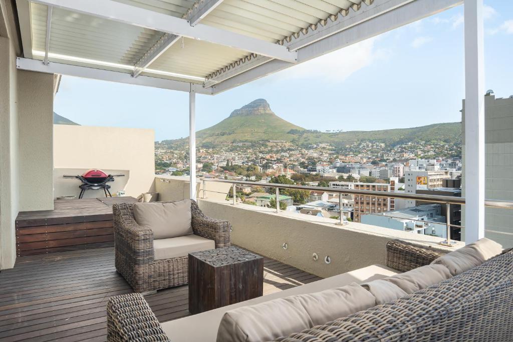 a living room with a couch and chairs on a balcony at Four Seasons Apartments in Cape Town