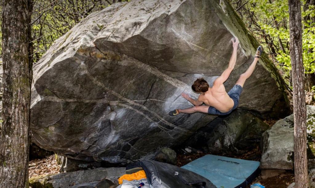 a man climbing on a rock in the woods at La Pergola by Quokka 360 - for mountain sports enthusiasts in Lavorgo