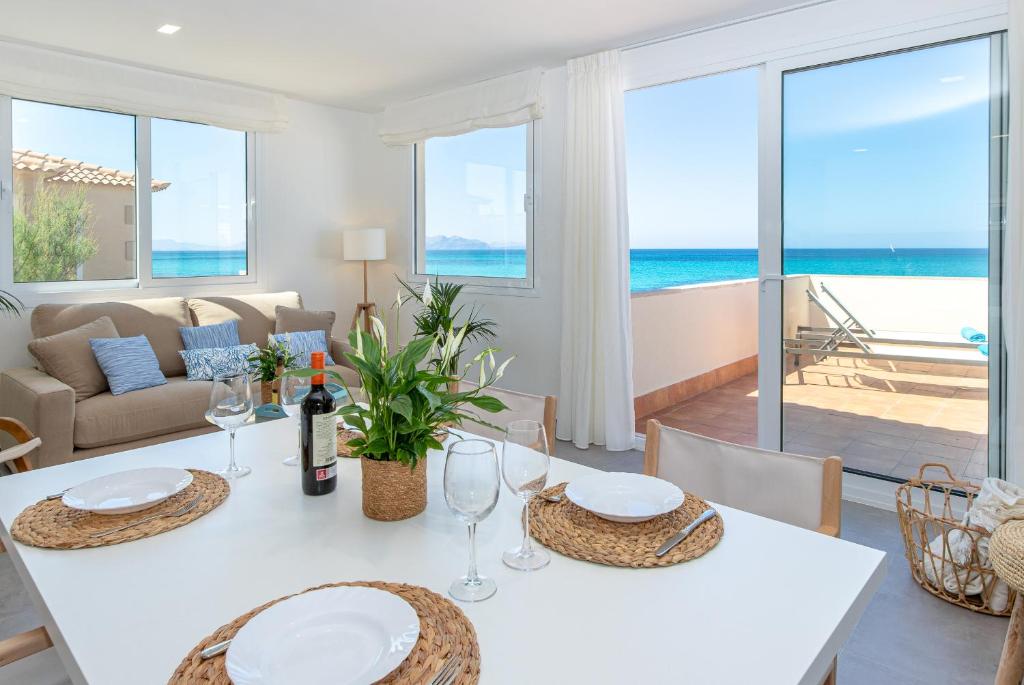 a dining room with a white table with a view of the ocean at Apartment Jedy Balear By homevillas360 in Son Serra de Marina