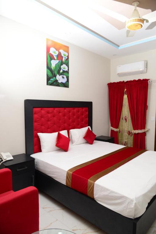 拉合爾的住宿－Hotel Deluxe Johar Town Lahore，一间卧室设有一张大床和红色床头板