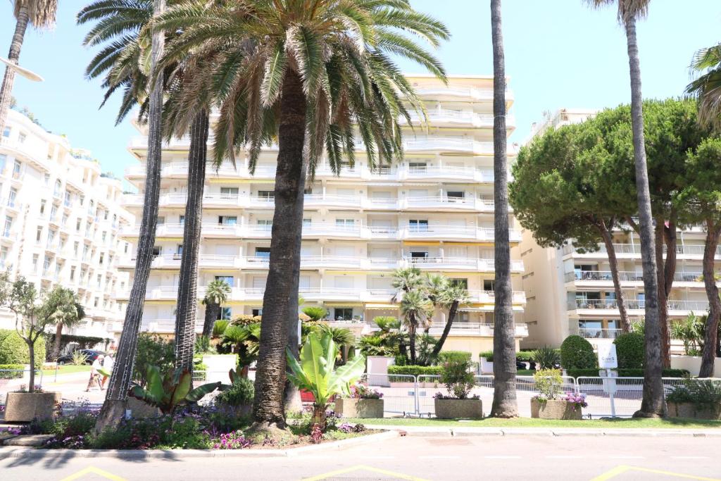 un grand bâtiment blanc avec des palmiers devant dans l'établissement 1 Bedroom Henri IV on the Croisette 240, à Cannes