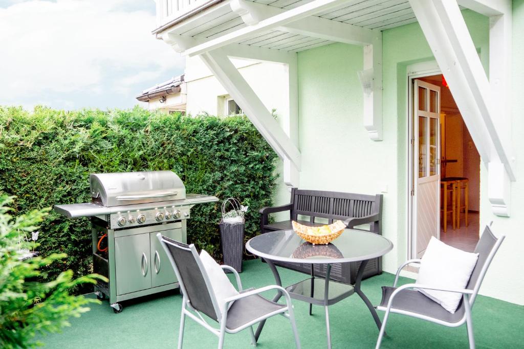 eine Terrasse mit einem Tisch, Stühlen und einem Grill in der Unterkunft Alva in Sondershausen