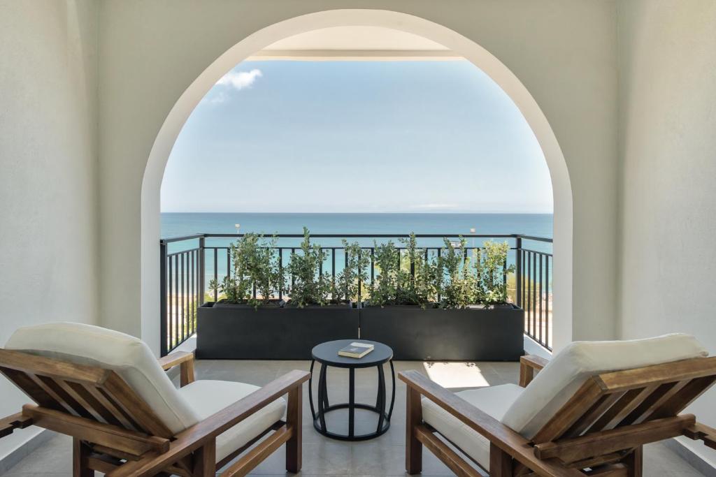 a balcony with two chairs and a view of the ocean at Bitzaro Boutique Hotel in Zakynthos Town