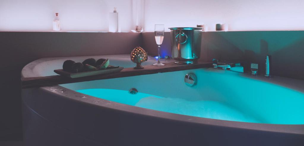 Le Dimore del Borgo - Room & Breakfast في كامبومارينو: حوض استحمام أزرق في الحمام مع كوب من النبيذ