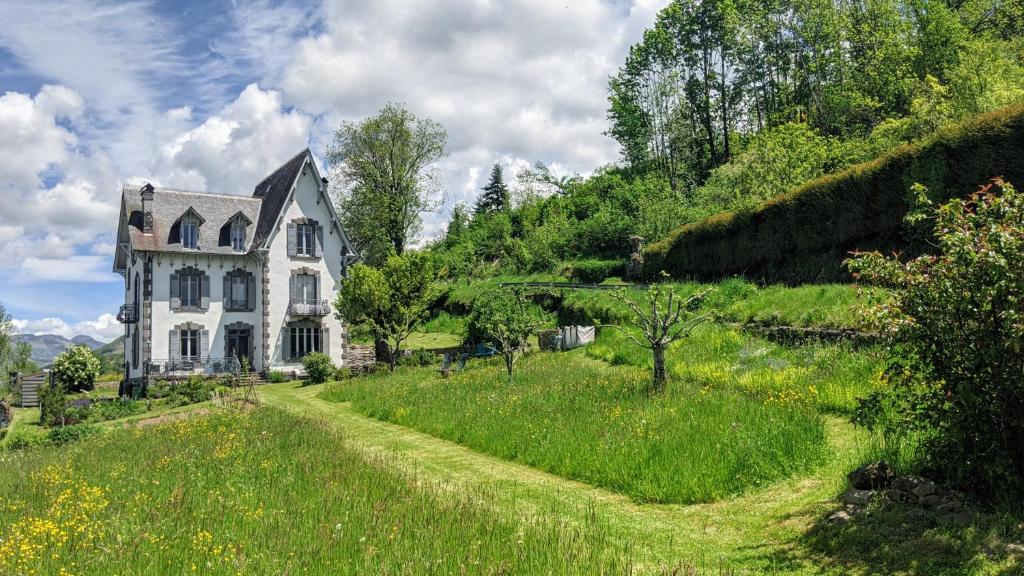 una casa vieja en una colina con un camino de tierra en La Maison Normande, en Saint-Cirgues-de-Jordanne