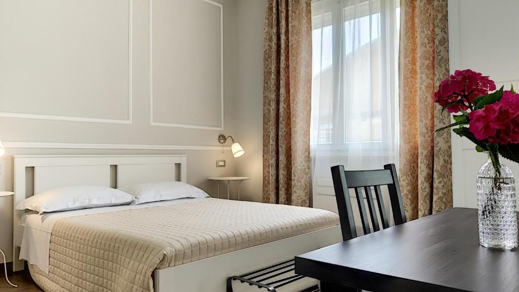 Un dormitorio con una cama y una mesa con un jarrón de flores en LA DAMA ROOM&BREAKFAST, en Russi