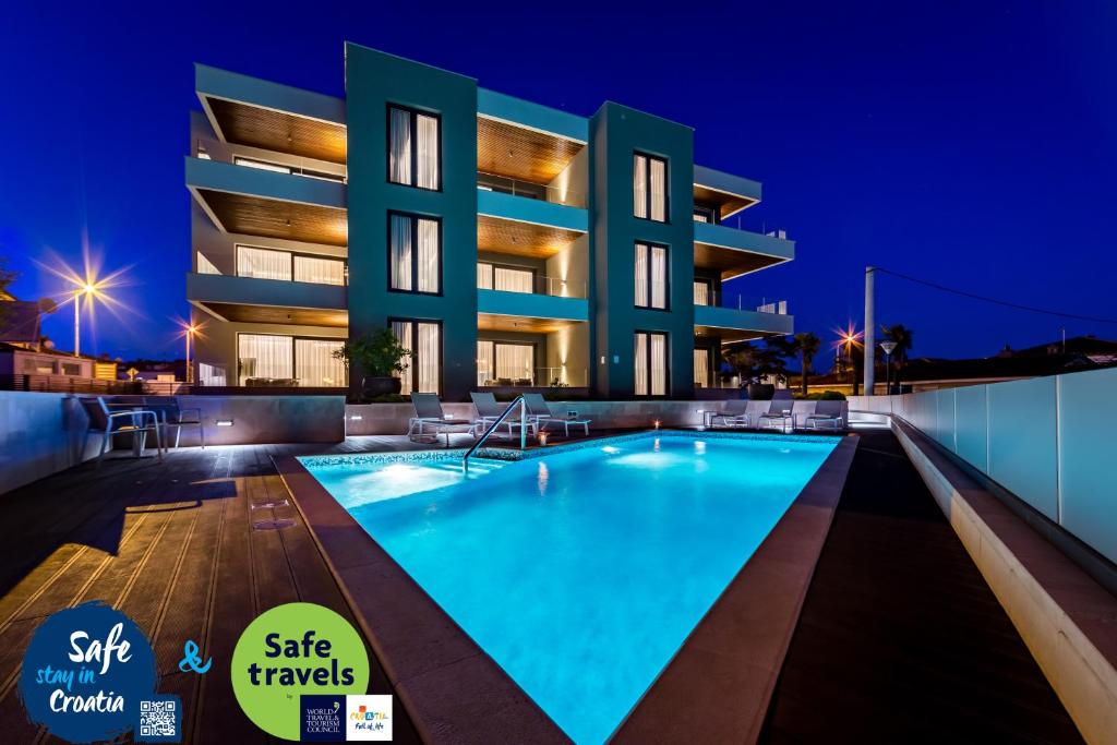 a swimming pool in front of a building at night at Rocca Riviera Umag Luxury Apartments in Umag