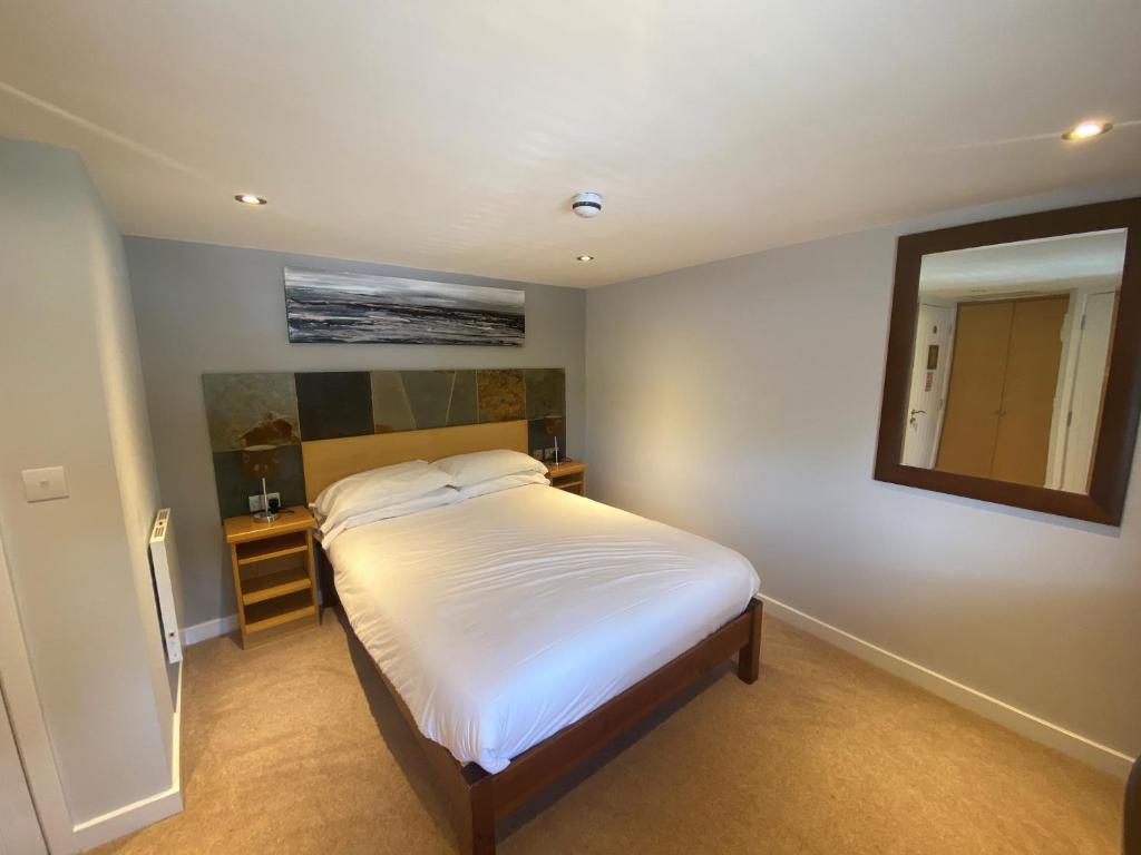 Schlafzimmer mit einem weißen Bett und einem Spiegel in der Unterkunft The King and Queen in West Malling