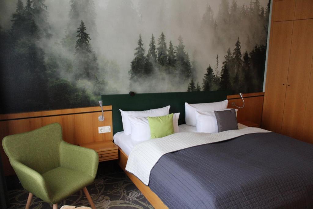 a bedroom with a bed and a green chair at Hotel Rennsteig in Masserberg