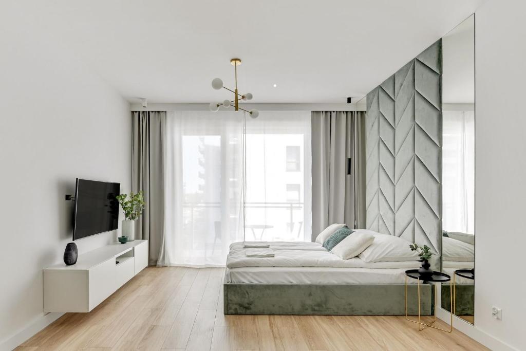 a white bedroom with a large bed and a tv at Grand Apartments - Bastion Wałowa Studio in Gdańsk