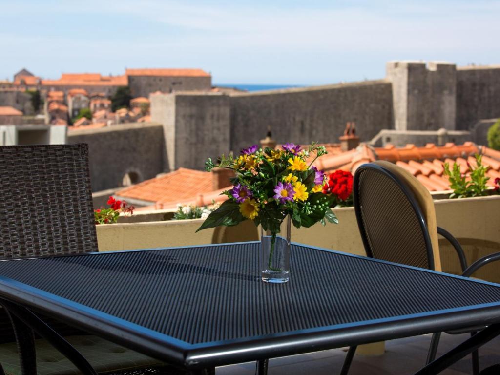un jarrón de flores sentado en una mesa en un balcón en Apartments Biba, en Dubrovnik