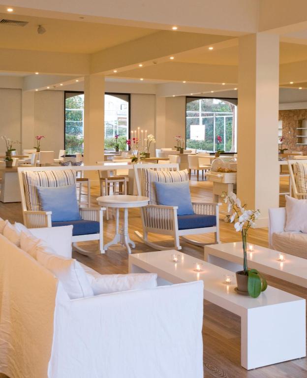 a lobby with white chairs and tables and tablesktop at Sandy Beach Hotel & Spa - ex Sentido in Larnaca