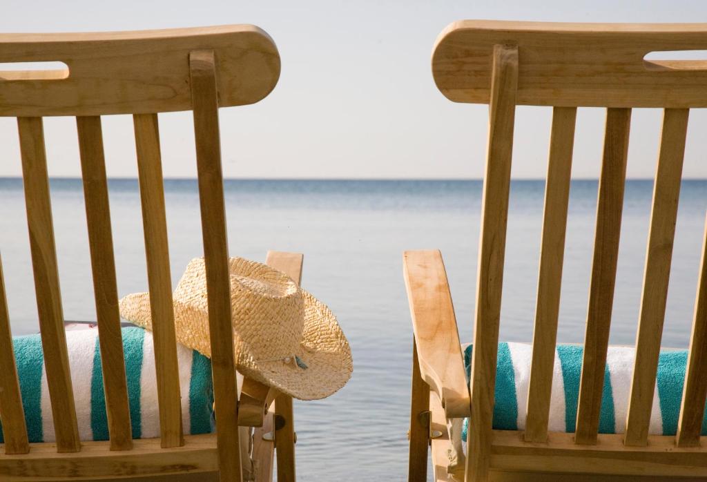 two chairs with a straw hat sitting next to the water at Sandy Beach Hotel & Spa - ex Sentido in Larnaca