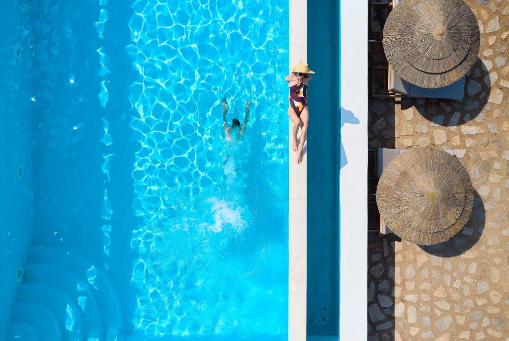 - une vue sur la piscine avec un homme et un parasol dans l'établissement EmGard Suites Kythnos, à Kythnos