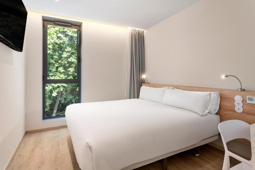 a bedroom with a white bed and a window at B&B HOTEL Lisboa Montijo in Montijo